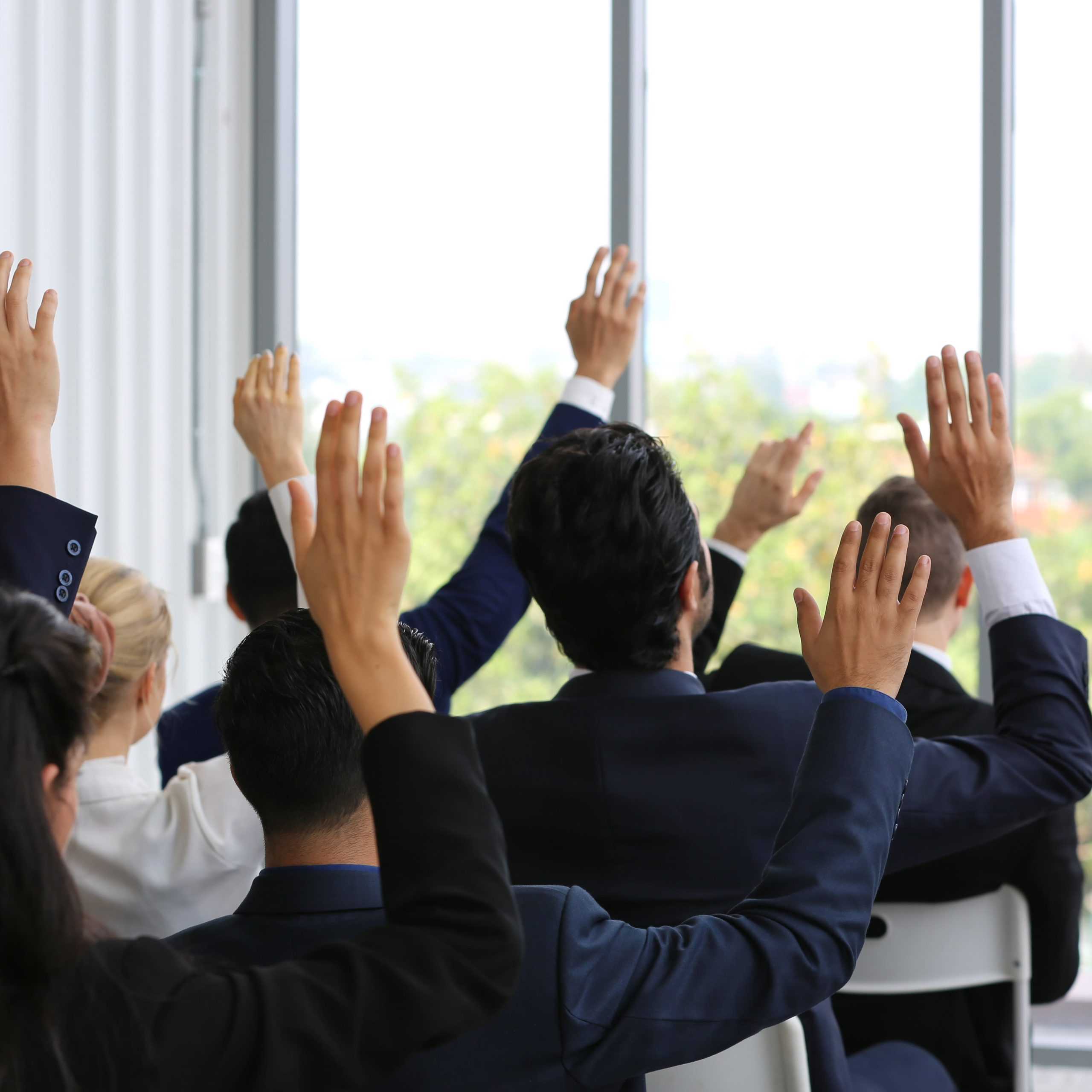 People raising hands in a corporate setting