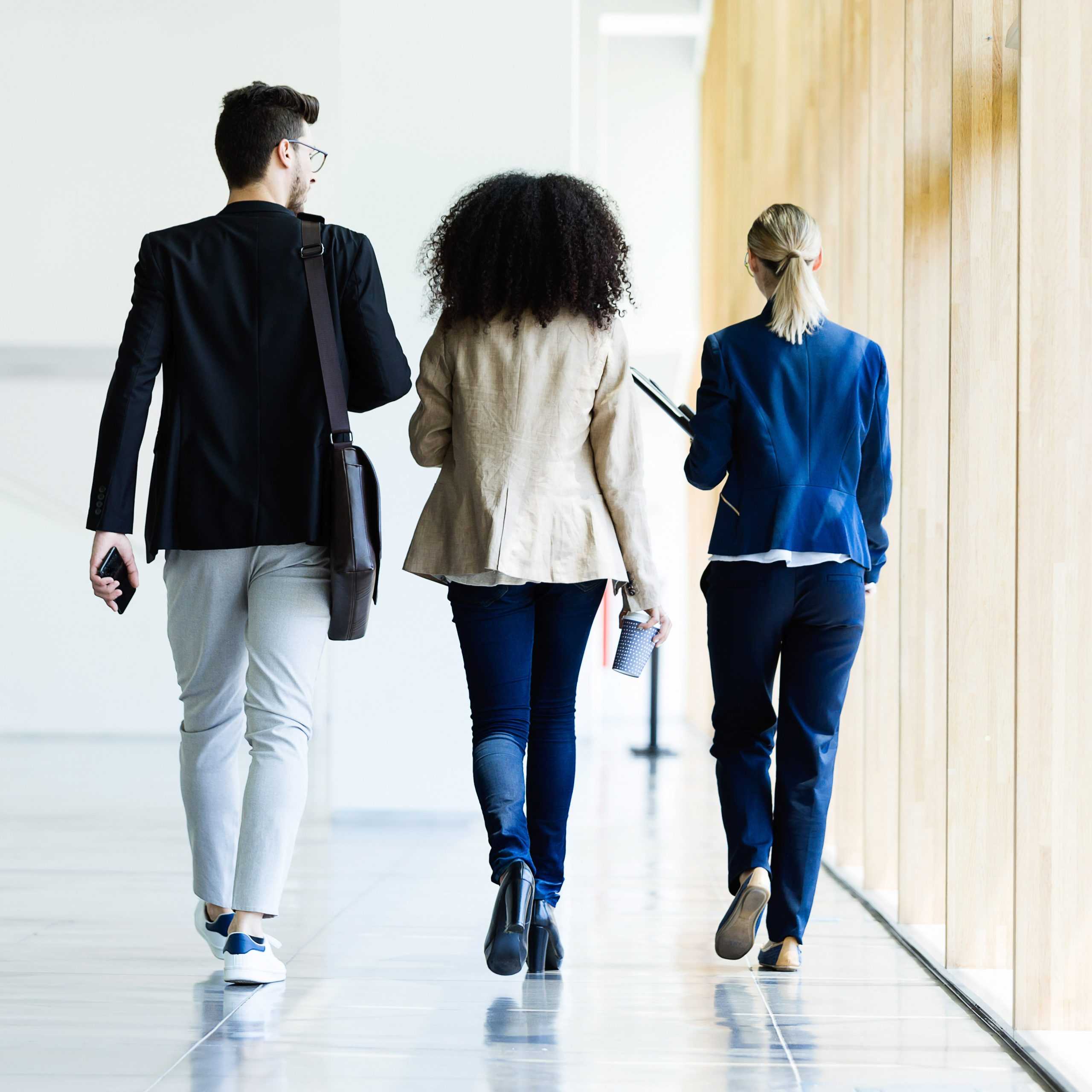 Three young business people walking and talking in a hallway