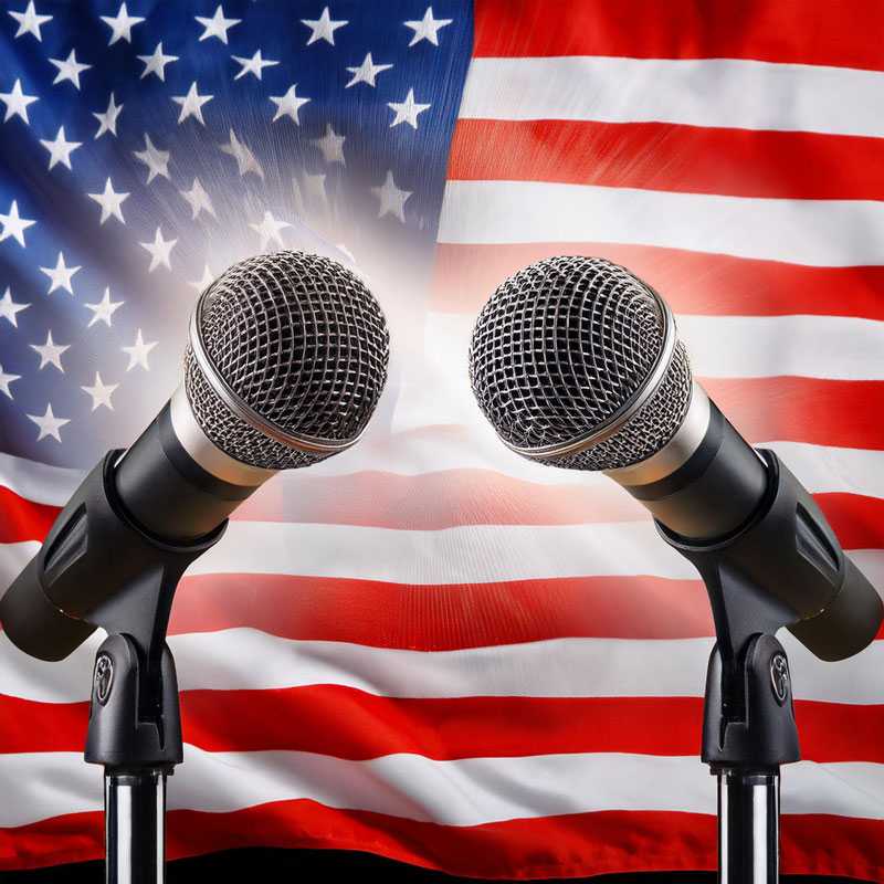 Two microphones in front of the U.S. flag